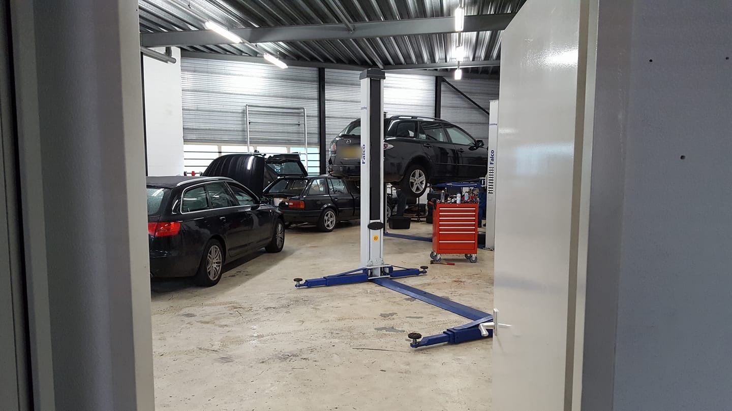 De werkplaats van Garagebedrijf Karol met auto's op en naast de hefbrug